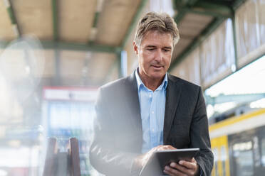 Mature businessman using tablet at station platform - DIGF08917