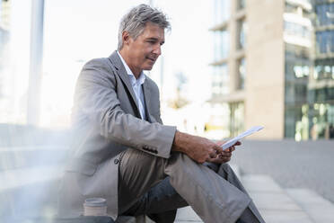 Mature businessman reviewing documents in the city - DIGF08933