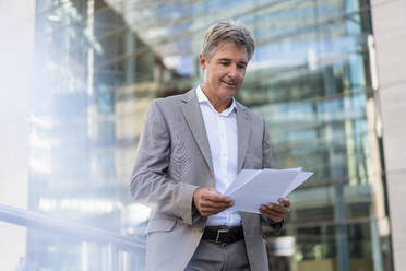 Mature businessman reviewing documents in the city - DIGF08935