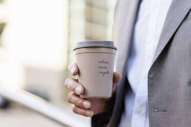 Close-up of businessman holding reusable takeaway coffee cup - DIGF08940