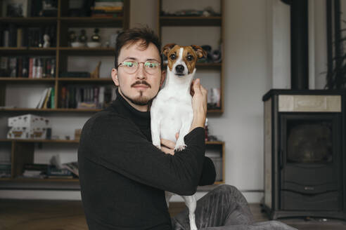 Junger Mann mit Jack Russel Terrier schaut in die Kamera - KMKF01140