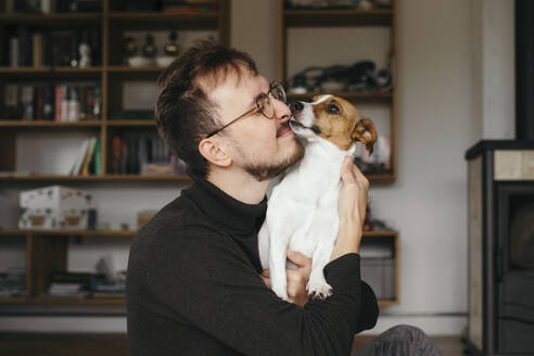 Junger Mann mit Jack Russel Terrier, leckend - KMKF01141