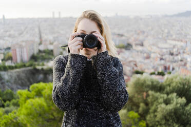 Young woman taking pictures above the city at sunrise, Barcelona, Spain - GIOF07708