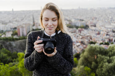 Young woman with camera above the city at sunrise, Barcelona, Spain - GIOF07709