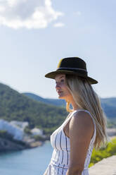 Young woman sitting on a wall and looking at distance, viewpoint in Ibiza - AFVF04229