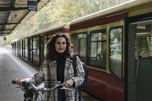 Frau mit Fahrrad auf einem U-Bahn-Bahnsteig, Berlin, Deutschland - AHSF01199