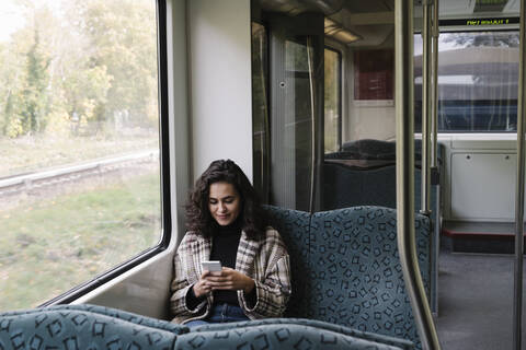 Junge Frau benutzt Smartphone in einer U-Bahn, lizenzfreies Stockfoto