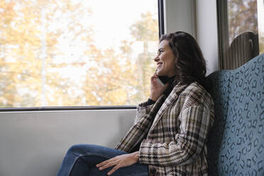 Smiling young woman on the phone on a subway - AHSF01213