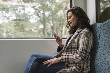 Young woman using smartphone on a subway - AHSF01214