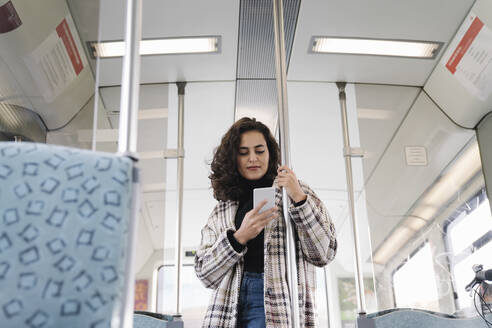 Junge Frau benutzt Smartphone in einer U-Bahn - AHSF01216