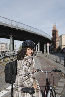 Porträt einer Frau mit einem Fahrrad in der Stadt, Berlin, Deutschland - AHSF01224