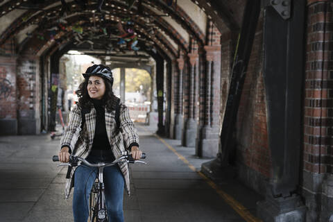 Porträt einer lächelnden Frau beim Fahrradfahren in der Stadt, Berlin, Deutschland, lizenzfreies Stockfoto