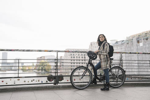 Frau mit Fahrrad auf einer Brücke in der Stadt, Berlin, Deutschland - AHSF01227