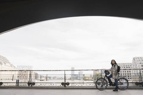 Frau mit Fahrrad auf einer Brücke in der Stadt, Berlin, Deutschland, lizenzfreies Stockfoto