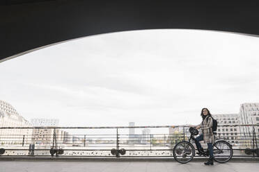 Frau mit Fahrrad auf einer Brücke in der Stadt, Berlin, Deutschland - AHSF01228