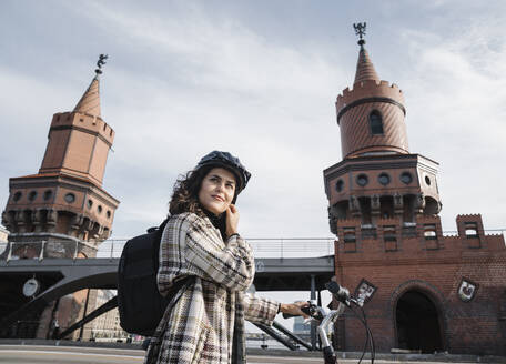 Frau mit einem Fahrrad in der Stadt an der Oberbaumbrücke, Berlin, Deutschland - AHSF01230
