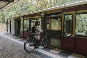 Woman with bicycle entering an underground train, Berlin, Germany - AHSF01240