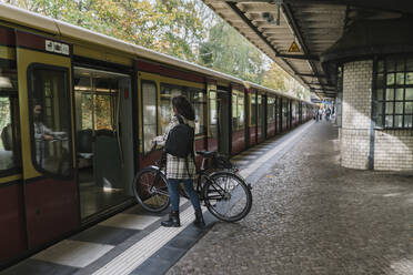 Woman with bicycle entering an underground train, Berlin, Germany - AHSF01241