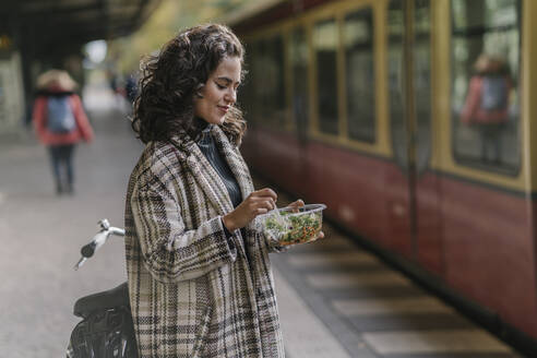 Frau beim Mittagessen auf einem U-Bahn-Bahnsteig, Berlin, Deutschland - AHSF01244