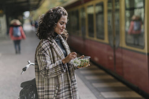 Woman having lunch on an underground station platform, Berlin, Germany - AHSF01244