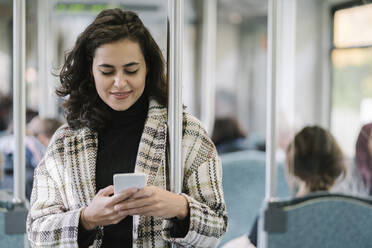 Junge Frau benutzt Smartphone in einer U-Bahn - AHSF01249