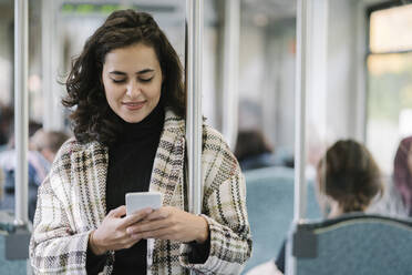 Young woman using smartphone on a subway - AHSF01249