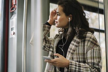 Young woman with earphones and smartphone on a subway - AHSF01251