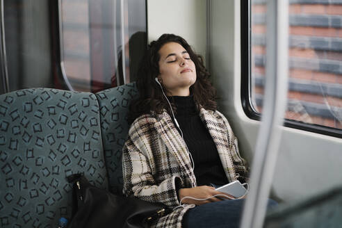 Junge Frau mit geschlossenen Augen entspannt sich in einer U-Bahn - AHSF01253