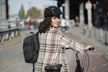 Porträt einer Frau mit einem Fahrrad in der Stadt, Berlin, Deutschland - AHSF01254