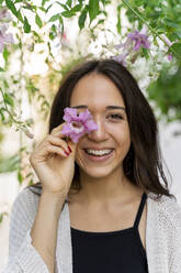 Porträt einer jungen Frau mit rosa Blume und verdecktem Auge - AFVF04233