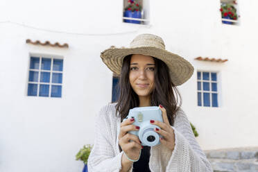 Junge Frau mit Sonnenhut und blauer Kamera in der Hand - AFVF04242