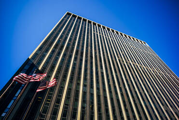 USA, New York, New York City, amerikanische Flaggen vor hohem Wolkenkratzer - OCMF00888