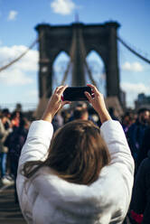 Woman taking a picture of Brooklyn Bridge, New York, United States - OCMF00895