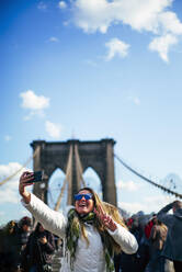 Happ-Frau macht ein Selfie auf der Brooklyn Bridge, New York, Vereinigte Staaten - OCMF00896