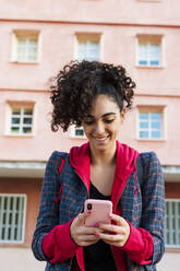 Porträt einer glücklichen jungen Frau, die ein Mobiltelefon benutzt - ERRF02037