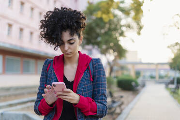 Porträt einer jungen Frau, die ein Mobiltelefon im Freien benutzt - ERRF02038
