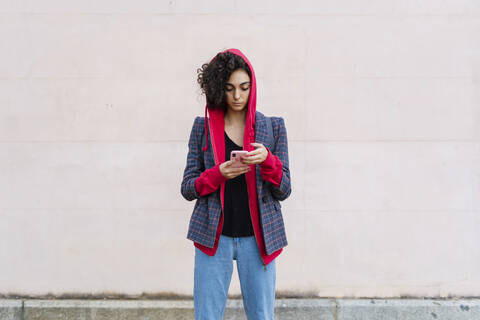 Porträt einer jungen Frau, die ein Mobiltelefon im Freien benutzt, lizenzfreies Stockfoto