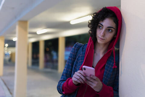Porträt einer jungen Frau mit Mobiltelefon am Abend, lizenzfreies Stockfoto