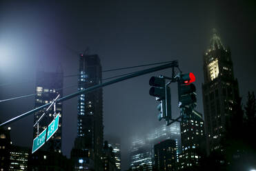 USA, New York, New York City, Ampel vor beleuchteten Wolkenkratzern bei Nacht - OCMF00908