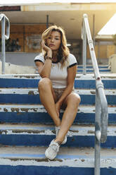 Portrait of woman sitting on steps - CAVF69201