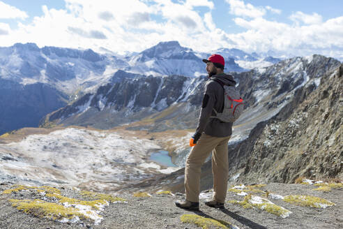 Wanderer betrachtet die Aussicht, während er auf dem Gipfel eines Berges steht - CAVF69219