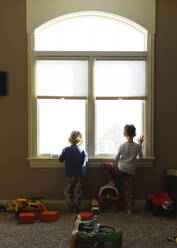 Rückansicht von Jungen, die durch ein Fenster zu Hause schauen - CAVF69237