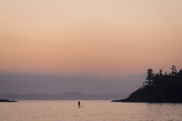 Silhouette person paddleboarding in lake - CAVF69259