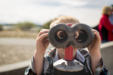 Porträt eines Jungen, der durch ein Fernglas schaut - CAVF69277