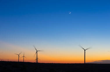 Silhouette Windräder drehen sich gegen den blauen Himmel bei Sonnenuntergang - CAVF69337