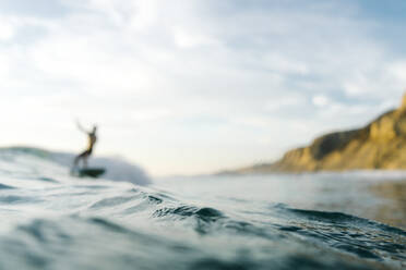 Unscharfes Bild eines Mannes beim Surfen auf dem Meer vor bewölktem Himmel - CAVF69367