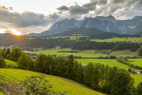 Blick auf einen vorbeifahrenden Zug und Sonnenuntergang über den Bergen um Oberhaus, Steiermark, Österreich, Europa - RHPLF12796