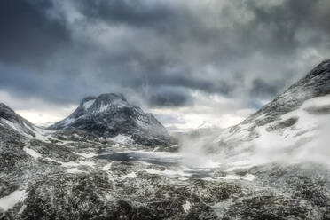 Storm clouds over Olaskarsvatnet lake at feet of the snowcapped Olaskarstind mountain, Venjesdalen valley, Andalsnes, Norway, Scandinavia, Europe - RHPLF12846