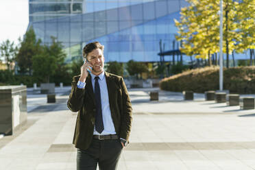 Businessman on the phone in urban business district, Madrid, Spain - KIJF02734