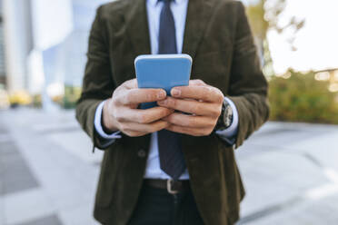 Close-up of businessman using smartphone outdoors - KIJF02759